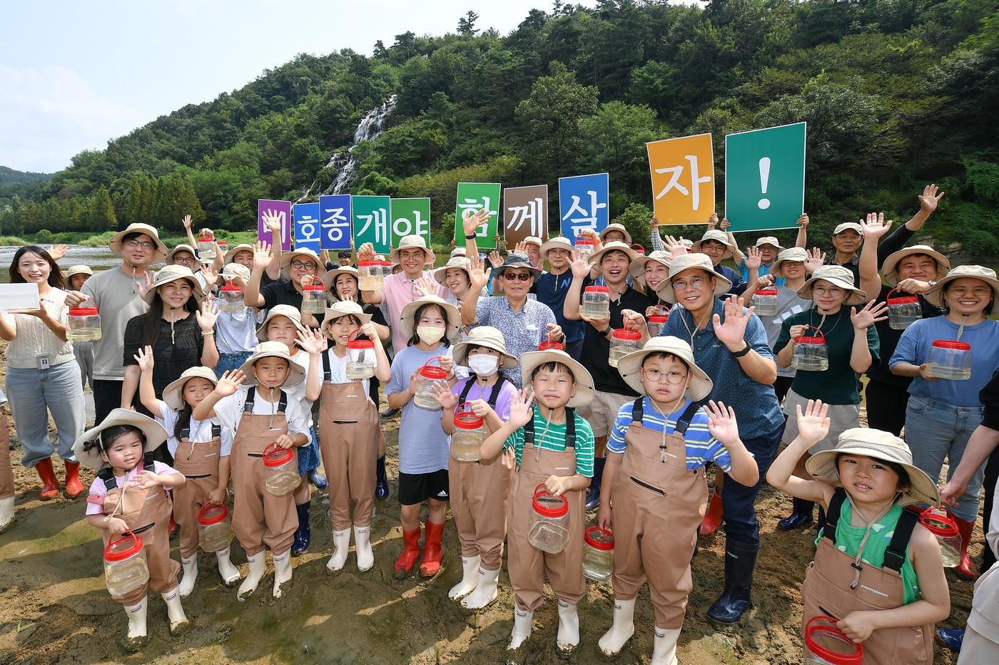 본문 이미지 - 현대모비스가 멸종위기종 복원을 위해 23일 미호종개 방류행사를 개최했다. 현대모비스 임직원과 가족, 지역주민들이 충북 진천군 초평면 미르숲 입구에서 미호종개를 방류하는 모습(현대모비스 제공). 