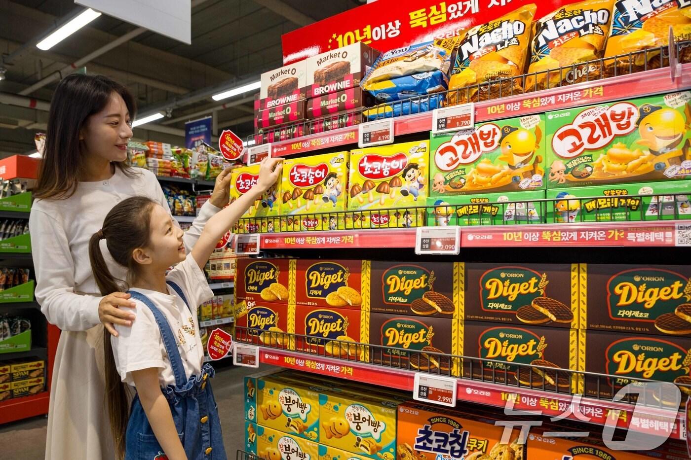 29일 서울 강서구 한 대형마트에서 모델이 오리온 '10년 이상 뚝심 있게 지켜온 가격' 특별 행사 상품을 둘러보고 있다. 오리온은 10년 넘게 가격을 올리지 않은 브랜드 22개 중 고래밥, 초코송이, 촉촉한초코칩, 브라우니, 다이제 등 주요 제품을 할인 판매한다. (오리온 제공) 2024.8.29/뉴스1