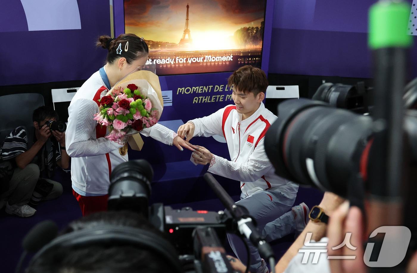 중국 배드민턴 황야총이 2일(한국시간) 프랑스 파리 라 샤펠 아레나에서 열린 배드민턴 혼합복식 금메달 결정전 시상식을 마치고 믹스트존을 향하던 중 대표팀 동료 류위첸으로부터 다이아몬드 반지와 프로포즈를 받고 있다. 이날 젱시웨이-황야총 조는 한국 대표팀 김원호-정나은을 상대해 스코어 2대0 승리를 거두며 금메달을 목에 걸었다. 2024.8.3/뉴스1 ⓒ News1 이동해 기자