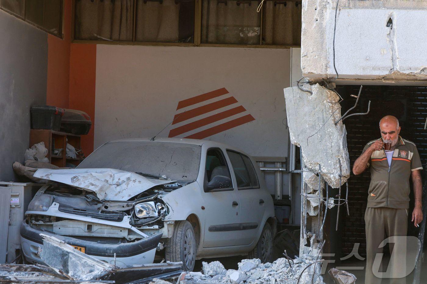 본문 이미지 - 이스라엘군의 대대적인 공격으로 무너져 내린 툴카렘 인근 누르샴스 난민 캠프의 건물 앞에서 30일 한 팔레스타인 노인이 늘 있는 일상인냥 느긋하게 담배를 피우며 차를 마시고 있다. 이스라엘군은 요르단 강 서안지역에서 사흘째 대규모 공세와 공습을 벌이고 있다. 2024.08.30 ⓒ AFP=뉴스1 ⓒ News1 권진영기자