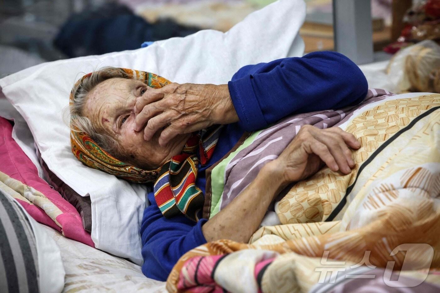 본문 이미지 - 우크라이나의 역침공에 집을 떠난 한 러시아 노파가 쿠르스크 모처의 민간인 대피시설 침대에 누워있는 모습. ⓒ AFP=뉴스1 ⓒ News1 권진영기자