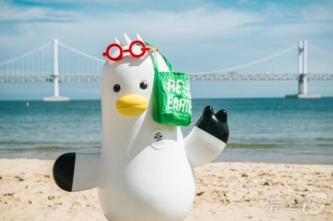 본문 이미지 - 2023년 광안리해수욕장에서 진행된 롯데백화점 환경정화 활동 현장에서 부산시소통캐릭터 부기가 기념사진을 찍고 있다(롯데백화점 제공)