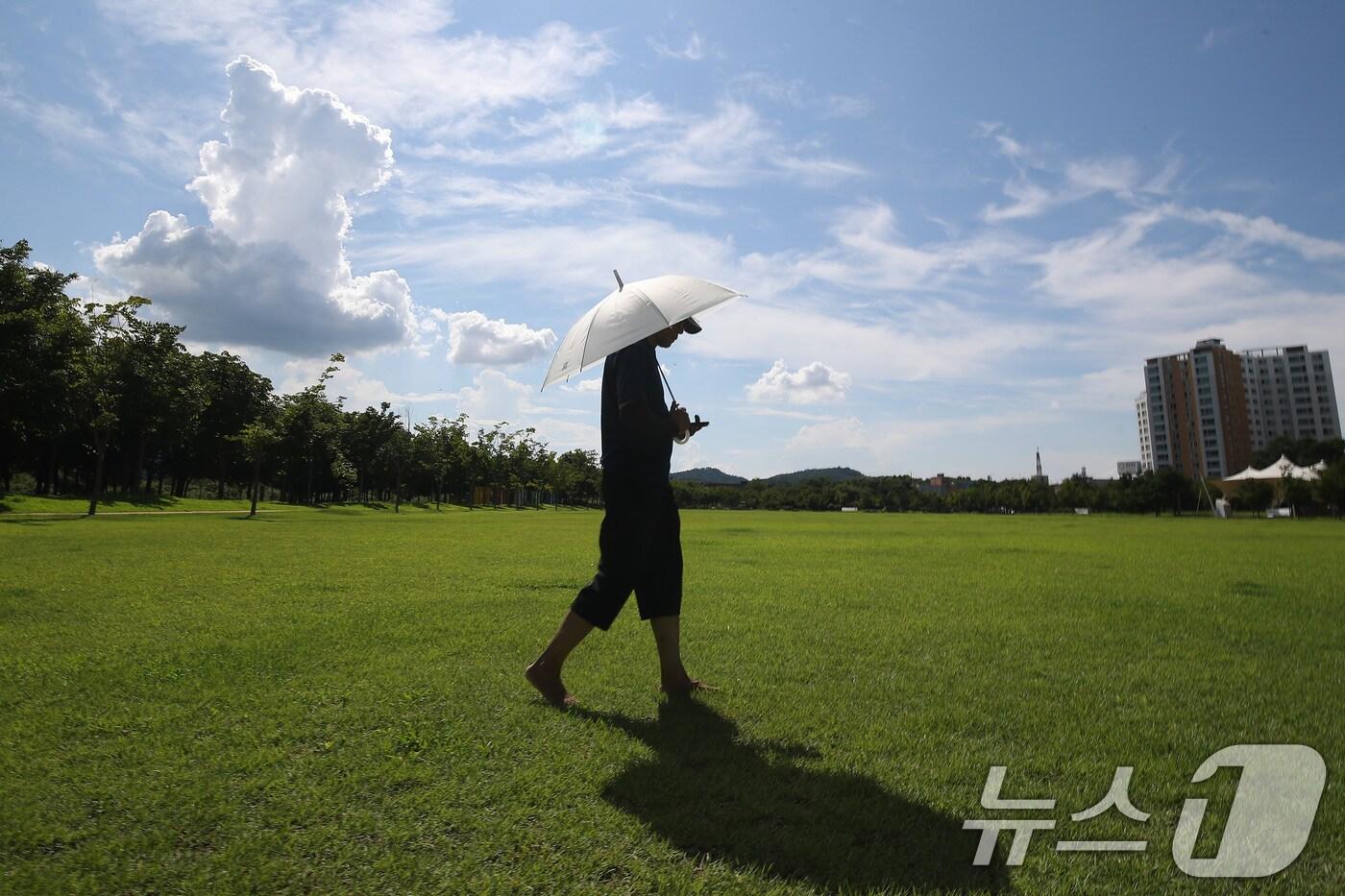 가을로 접어드는 입추(立秋)에도 폭염이 누그러질 기미를 보이지 않는다. 지난 6일 오후 텅 빈 대구 동구 율하체육공원에서 한 시민이 양산으로 뙤약볕을 가린 채 산책하고 있다. 2024.8.6/뉴스1 ⓒ News1 공정식 기자