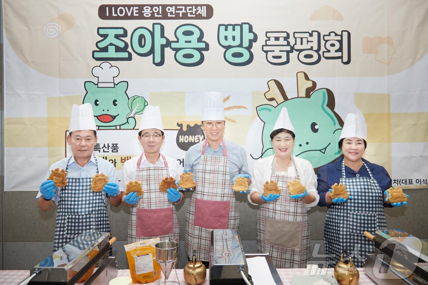 본문 이미지 - 용인시의회 의원연구단체 ‘I LOVE 용인’ 회원들이 6일 열린 연구과제 중간보고회에서 상품화를 추진하고 있는 ‘조아용빵’ 시제품을 들고 기념촬영을 하고 있다.(시의회 제공)