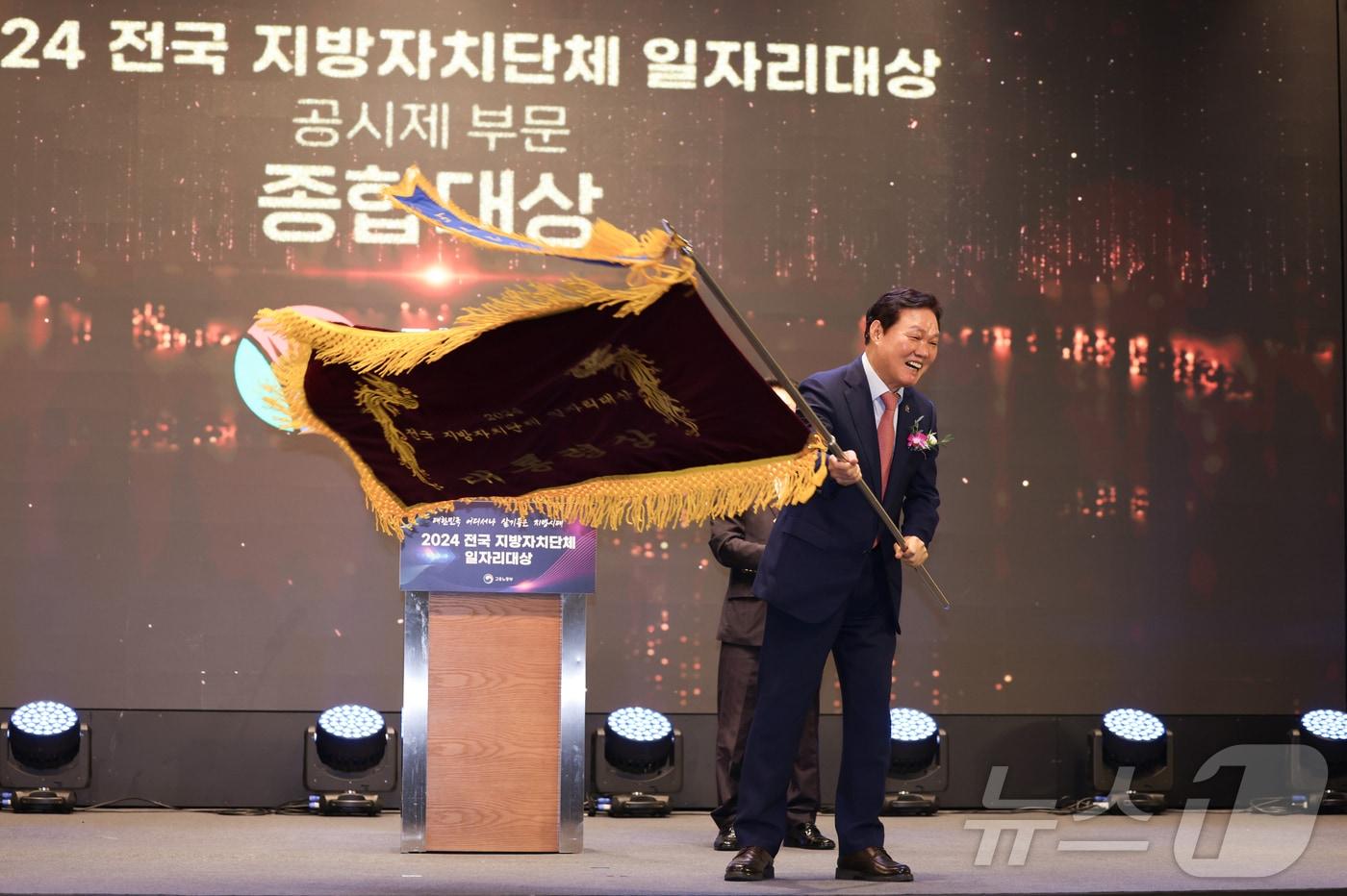 박완수 경남지사가 8일 서울에서 열린 '2024년 전국 지방자치단체 일자리대상' 시상식에서 대통령상으로 받은 기념기를 흔들고 있다.(경남도 제공)