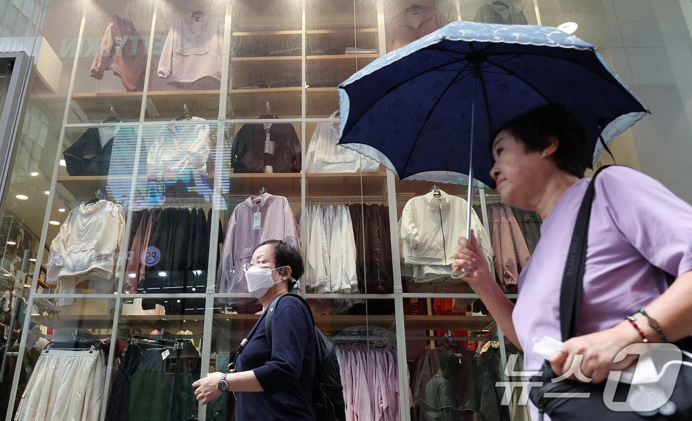 유례 없는 무더위가 이어지고 있는 19일 관광객들이 가을 옷이 전시된 의류매장 앞으로 지나가고 있다. 기2024.9.19/뉴스1 ⓒ News1 장수영 기자