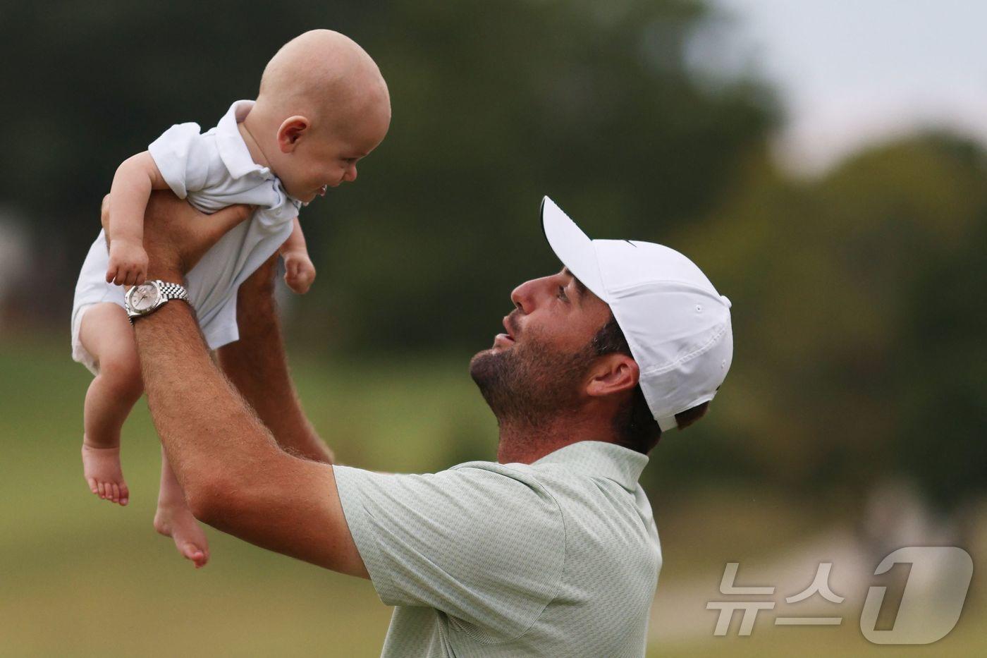 미국의 스코티 셰플러가 1일(현지시간) 조지아주 애틀랜타의 이스트레이크 골프클럽에서 열린 PGA 투어 페덱스컵 플레이오프 최종전 투어 챔피언십서 우승을 한 뒤 아들을 번쩍 들어 올리고 있다. 2024.09.02 ⓒ AFP=뉴스1 ⓒ News1 우동명 기자