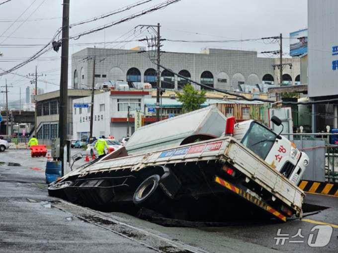 본문 이미지 - 21일 오전 8시45분께 부산 사상구 한 도로에서 가로 10m, 세로 5m, 깊이 8m 가량의 대형 땅꺼짐 현상&#40;싱크홀&#41;이 발생해 도로에서 배수 지원을 하던 삼락119안전센터 배수 차량과 5톤 트럭이 빠져있다. &#40;부산소방재난본부 제공&#41; 2024.9.21/뉴스1 ⓒ News1 윤일지 기자