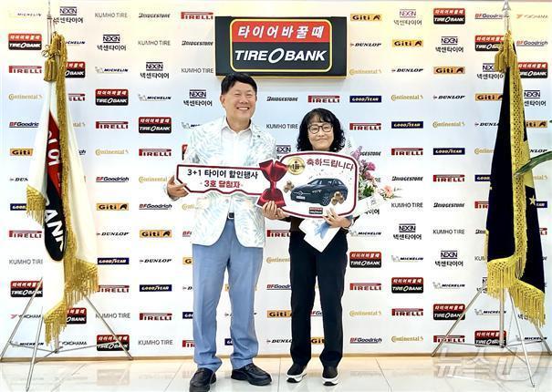 본문 이미지 - 전 국민 3+1 타이어 할인 행사 3회차 1등 당첨자 김정심씨(오른쪽)가 김정규 타이어뱅크 회장으로부터 벤트 차량 모형키를 받고 기념 촬영을 하고 있다.(타이어뱅크 제공) / 뉴스1 ⓒ News1 