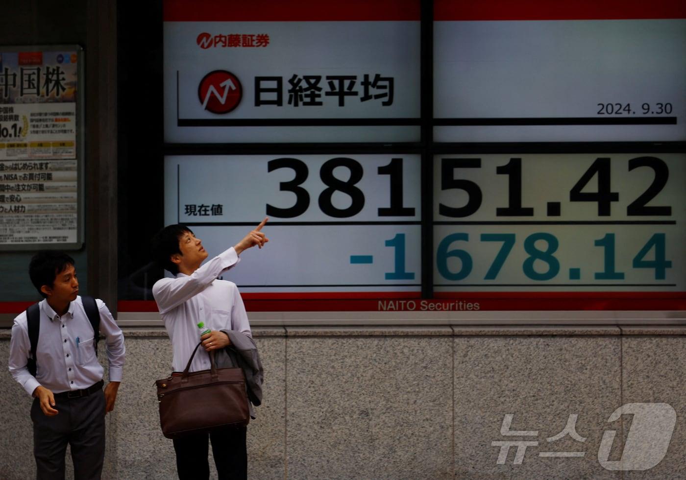 30일 일본 도쿄 도심에서 닛케이지수가 표시된 전광판 앞에서 시민들이 대화하고 있다. 2024.09.30 ⓒ 로이터=뉴스1 ⓒ News1 김지완 