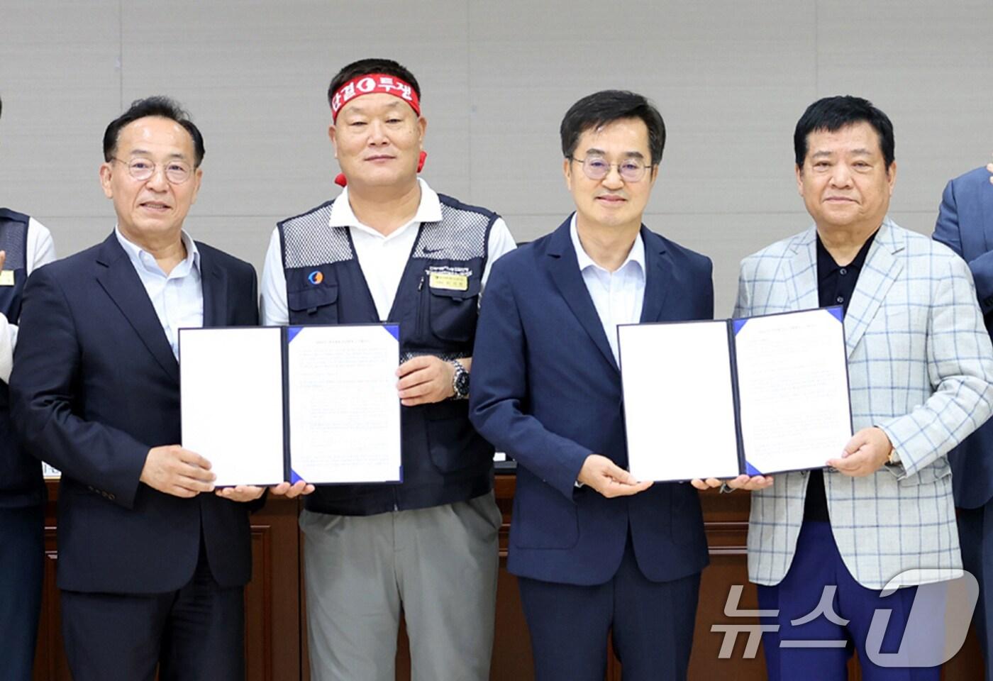 4일 오전 경기 수원시 경기지방노동위원회에서 밤샘 협상을 타결한 경기도 버스 노사 관계자들이 합의문을 들고 포즈를 취하고 있다. 왼쪽부터 김태기 중앙노동위원회 위원장, 이기천 경기도버스노동조합협의회 의장, 김동연 경기도지사, 김기성 경기도버스운송사업조합 이사장. (경기도 제공) 2024.9.4/뉴스1