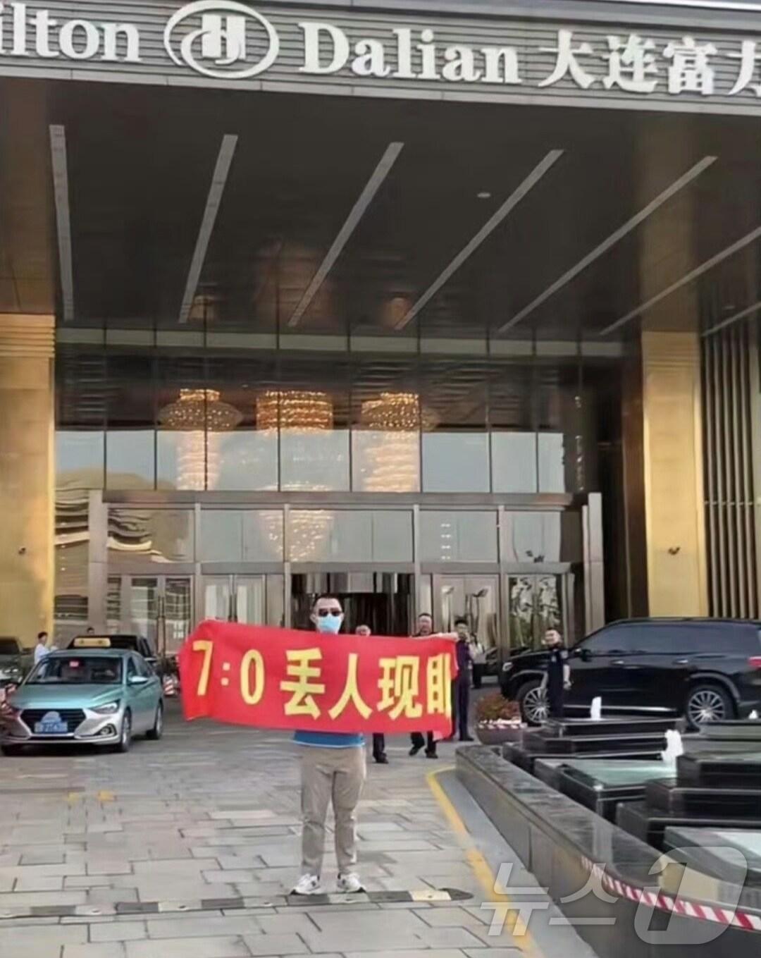 본문 이미지 - 중국 랴오닝성 다롄 힐튼 호텔 앞에 한 축구팬이 1인 시위를 하고 있다. (웨이보 갈무리)