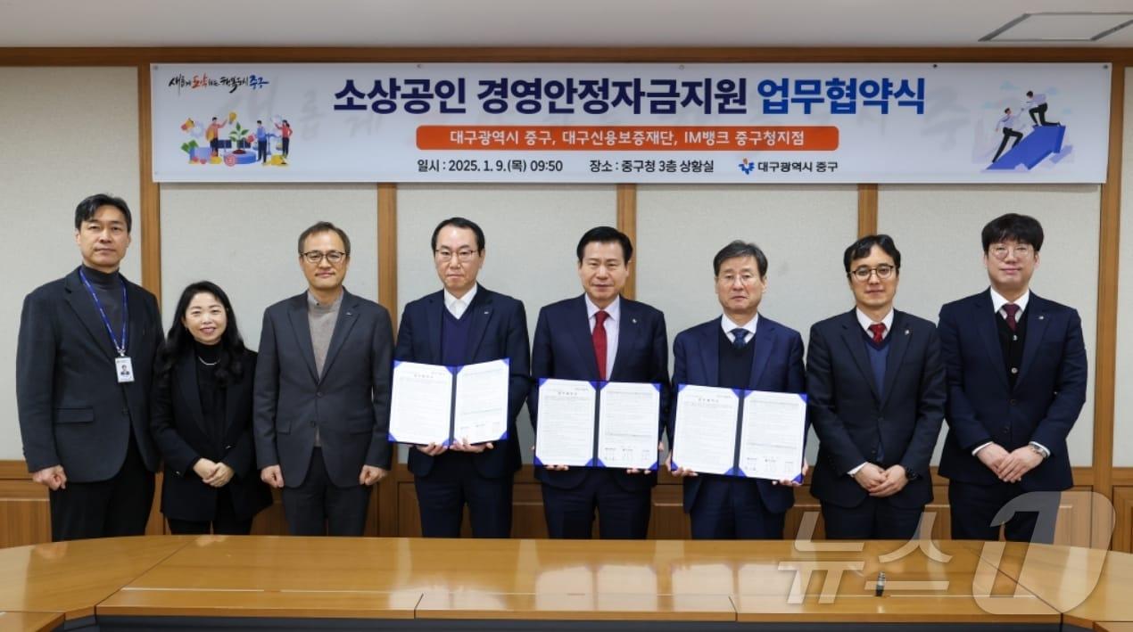 본문 이미지 - 박진우 대구신용보증재단 이사장(오른쪽 세번째)이 류규하 중구청장(왼쪽 다섯번째)과 소상공인 경영안정자금지원 업무협약을 체결한 후 협약서를 펼쳐 보이고 있다.(대구신보 제공)