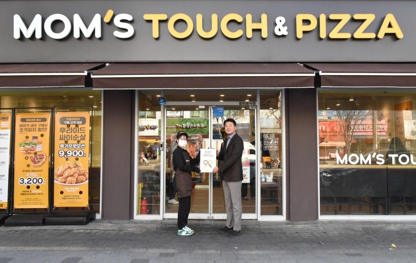 맘스터치 목동점에서 열린 최우수 매장 현판식에서 &#40;오른쪽&#41;이진영 맘스터치앤컴퍼니 가맹사업실장과 목동점 이서영 점주가 기념촬영을 하고 있다&#40;맘스터치앤컴퍼니&#41;.