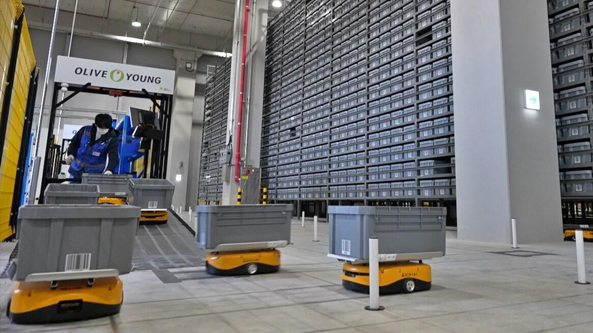 본문 이미지 - 물류 작업자가 자율 이동 로봇에 상품을 담고 있는 모습.(올리브영제공)