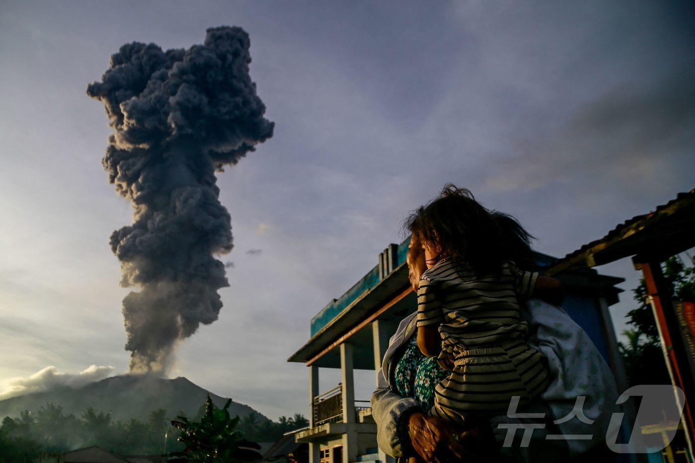 15일(현지시간) 인도네시아 북말루쿠의 웨스트 할마헤라에서 본 이부 화산이 폭발해 검은 화산재 기둥이 솟아 오르는 모습을 주민이 바라 보고 있다. 2025.01.16 ⓒ AFP=뉴스1 ⓒ News1 우동명 기자
