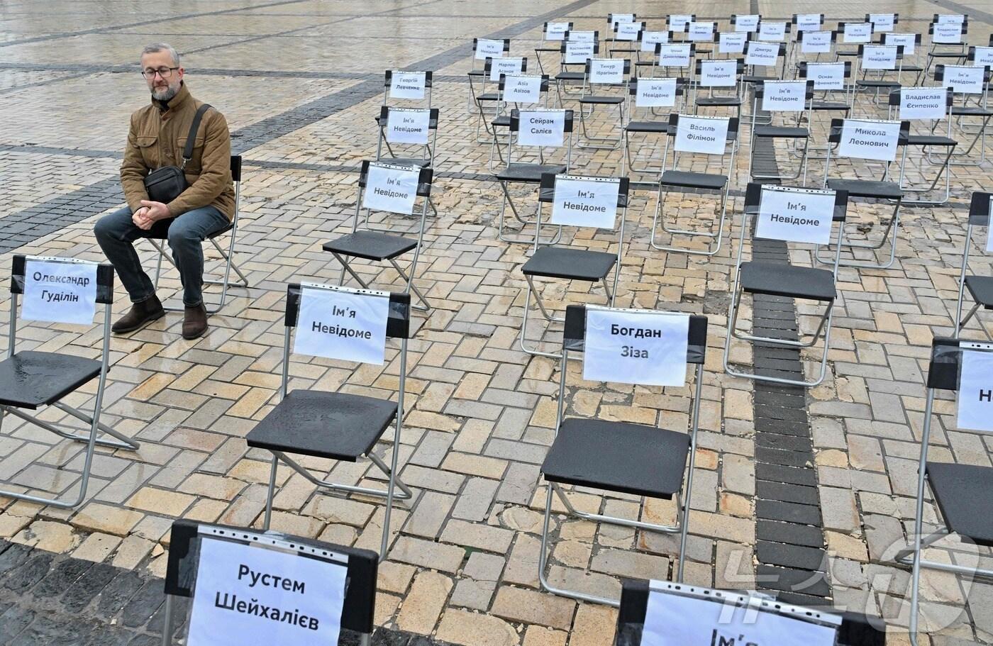 본문 이미지 - 우크라이나 키이우 중심부에서 과거 러시아 점령지에서 수감됐던 언론인 나리만 드젤리얄이 러시아에서 실종되거나 수감된 언론인·작가·문화인·인권 운동가의 이름이 적힌 의자들 사이에 앉아 '빈 의자의 날'을 기념하고 있다. 2024.11.15/ ⓒ AFP=뉴스1 ⓒ News1 권진영 기자