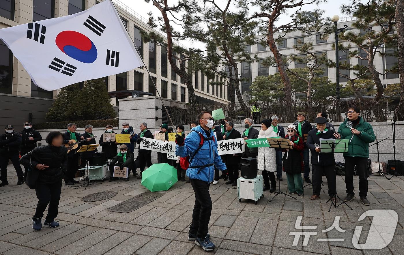 내란 우두머리 혐의로 구속된 윤석열 대통령의 탄핵 사건 3차 변론기일을 하루 앞둔 20일 오후 서울 종로구 헌법재판소 앞에서 한 윤 대통령 지지자가 태극기를 흔들며 전원일치 파면 촉구 기자회견 앞을 지나가고 있다. 한편, 윤 대통령 측은 구속 후 고위공직자범죄수사처(공수처)의 두 번째 부름에도 응하지 않기로 했지만 헌법재판소의 탄핵심판에는 곧 출석할 것이라고 밝혔다. 2025.1.20/뉴스1 ⓒ News1 김진환 기자