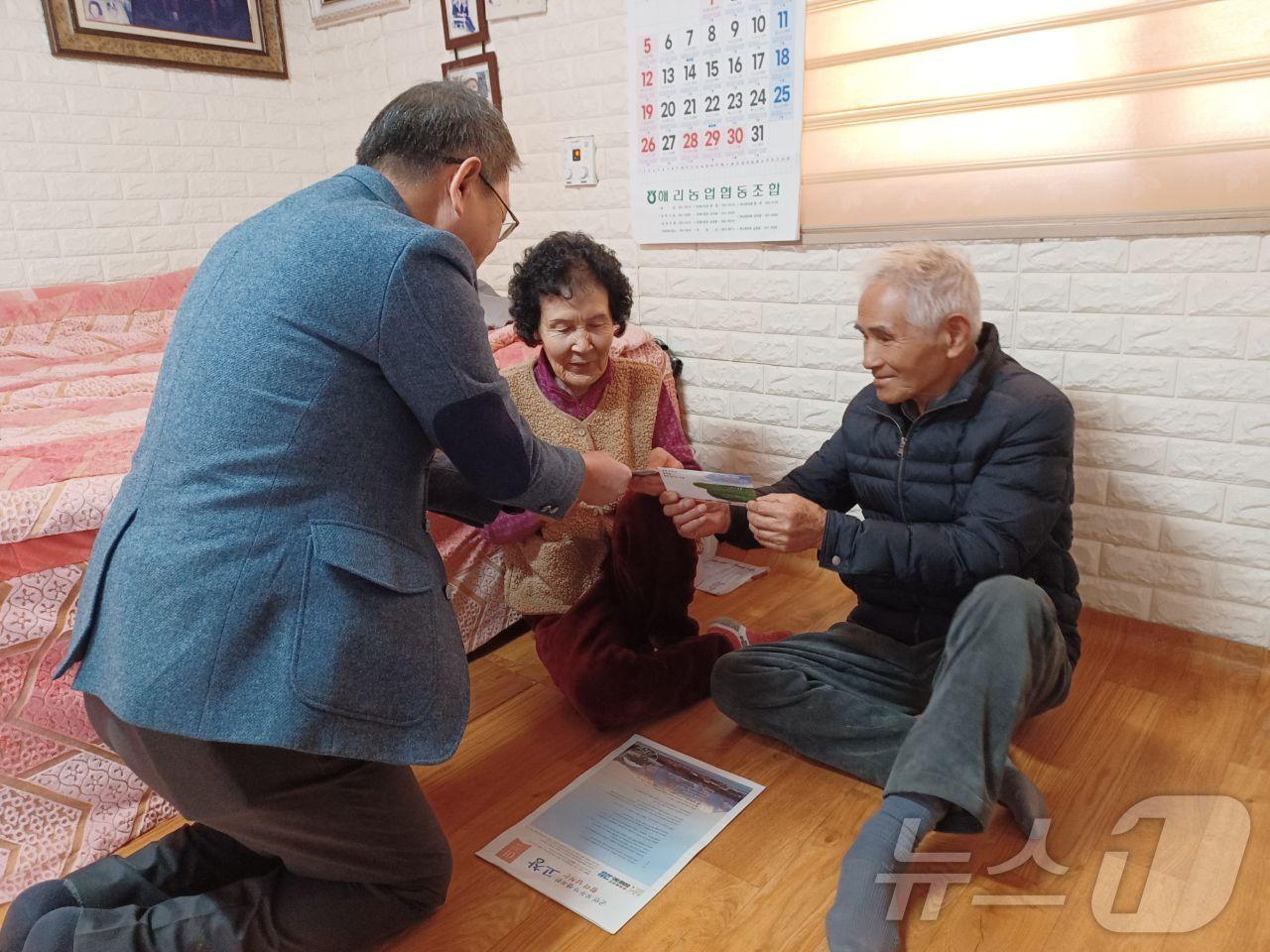 본문 이미지 -  고창군이 75세 이상 어르신에게 설 명절 전에 ‘경로 목욕 및 이‧미용비 지원금’을 지급한다. 해리면 직원이 어르신에게 상품권을 전하고 있다.(고창군 제공)2025.1.21/뉴스1