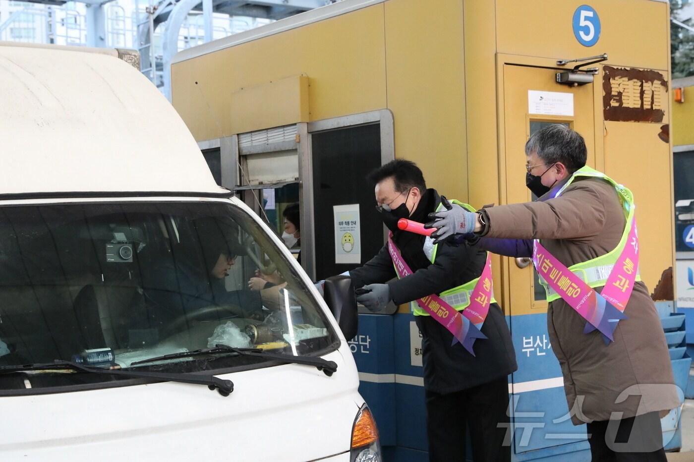 이성림 이사장(왼쪽)과 박태웅 도시기반본부장이 20일 오전 수영강변요금소에서 운전자에게 스마트톨링 안내문과 홍보기념품을 전달하고 있다.(부산시설공단 제공)