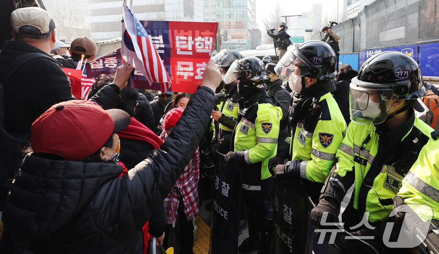 본문 이미지 - 21일 서울 종로구 헌법재판소 인근에서 열린 윤 대통령 지지자들의 탄핵 반대 집회에서 만일의 사태에 대비해 신체보호복을 착용한 경찰들이 경계근무를 서고 있다. 이날 윤 대통령은 헌재에서 열린 탄핵 심판 변론에 직접 출석했다. 2025.1.21/뉴스1 ⓒ News1 박지혜 기자