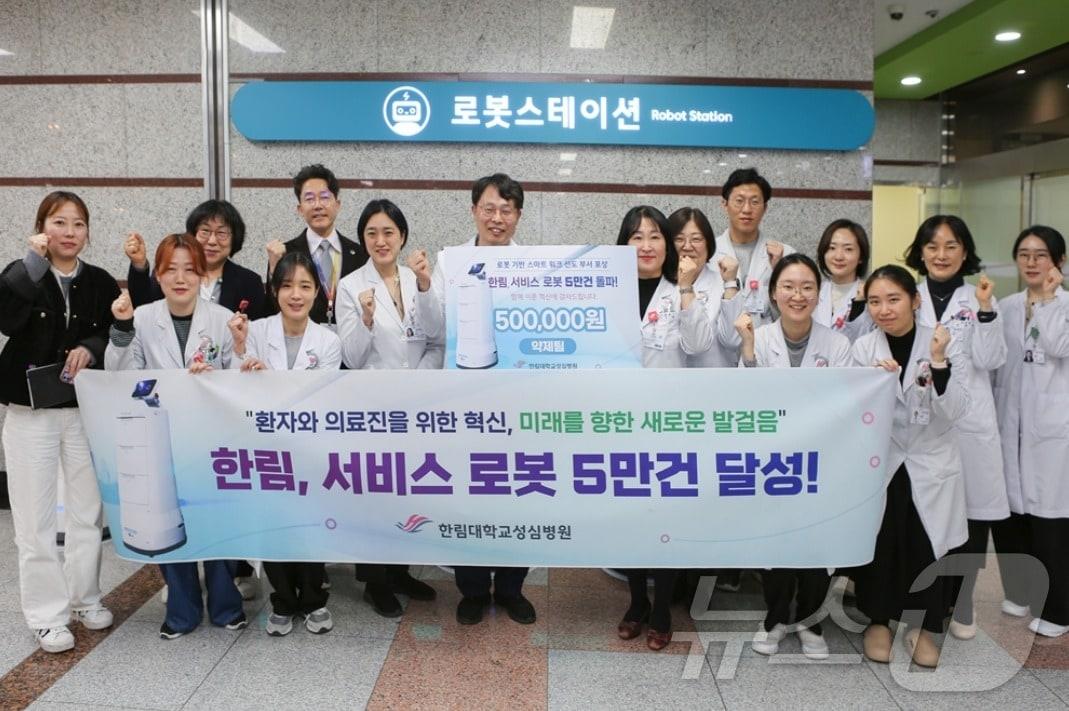 본문 이미지 - 한림대성심병원 의료진이 의료서비스로봇 사용 5만 건을 달성한 기념으로 사진 촬영을 하고 있다/한림대의료원 제공