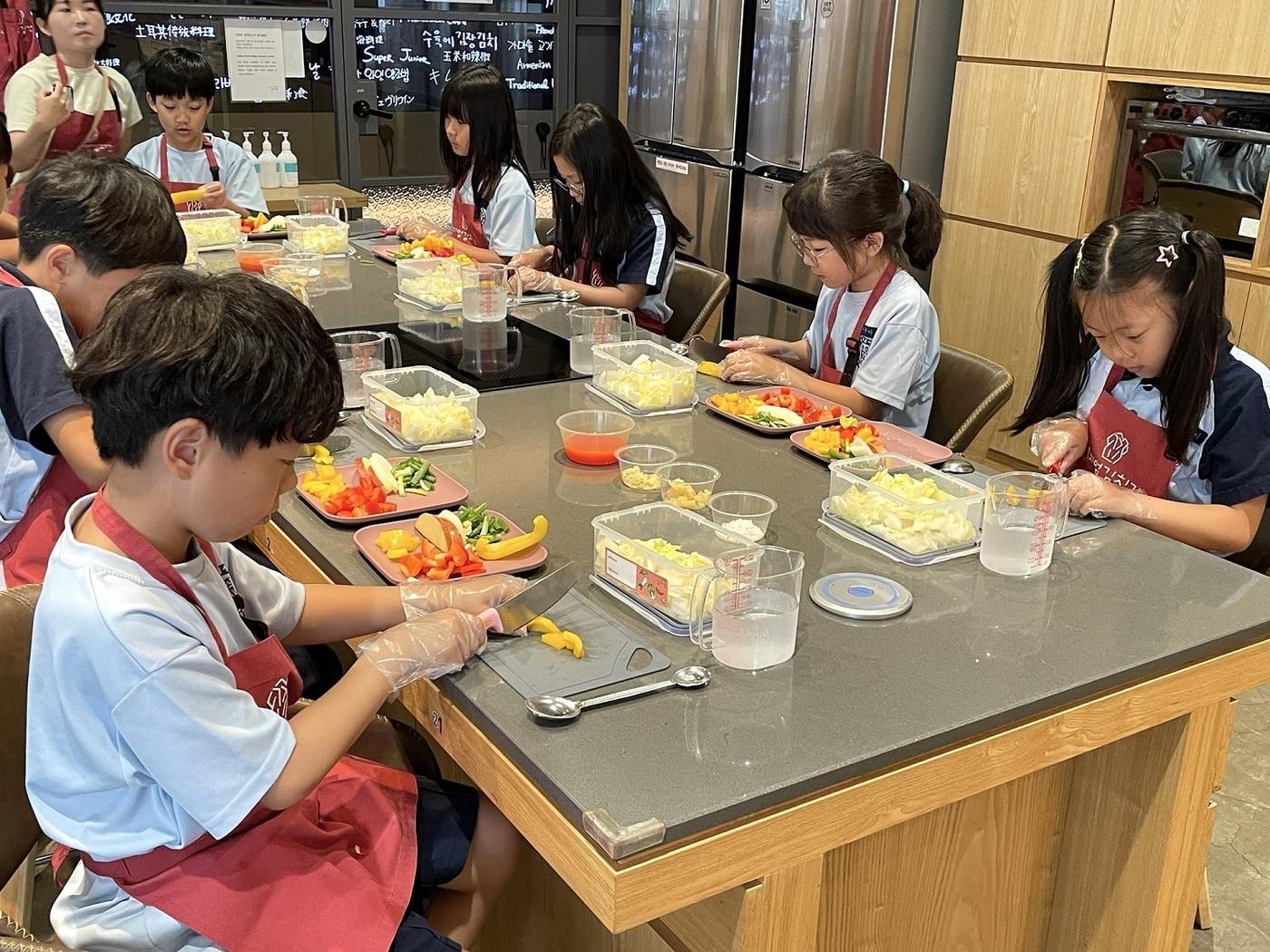 본문 이미지 -  풀무원 뮤지엄김치간의 대표 김치 체험 프로그램 ‘어린이 김치학교’에 참여한 어린이들이 다양한 제철 재료로 김치를 만들고 있다(풀무원 제공).