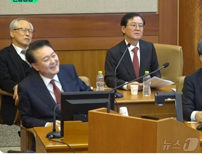 본문 이미지 -  윤석열 대통령이 23일 오후 헌법재판소에서 열린 탄핵심판 변론 때 김용현 전 국방부 장관 증언을 듣던 중 웃음을 지어 보이고 있다. (헌재 제공 동영상 갈무리) ⓒ 뉴스1