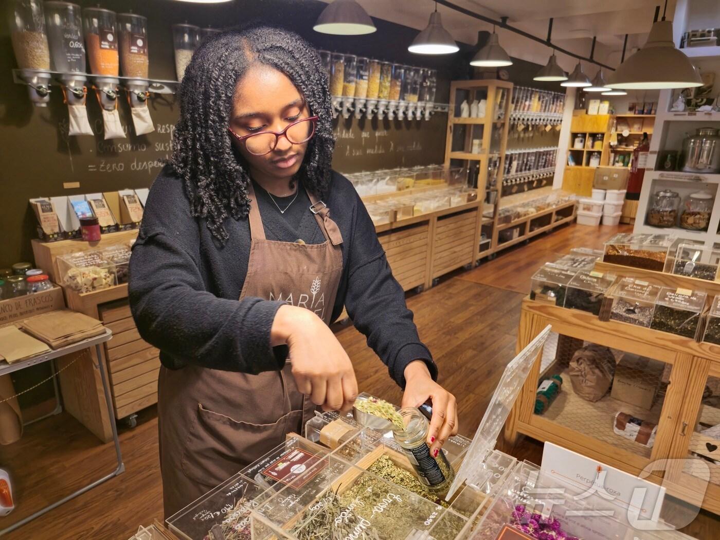 본문 이미지 - 23일 포르투갈 최초 제로웨이스트 식료품점 '마리아 그라넬' 점장 타티아나 뎀보가 식료품을 재활용기에 담고 있다. ⓒ 뉴스1