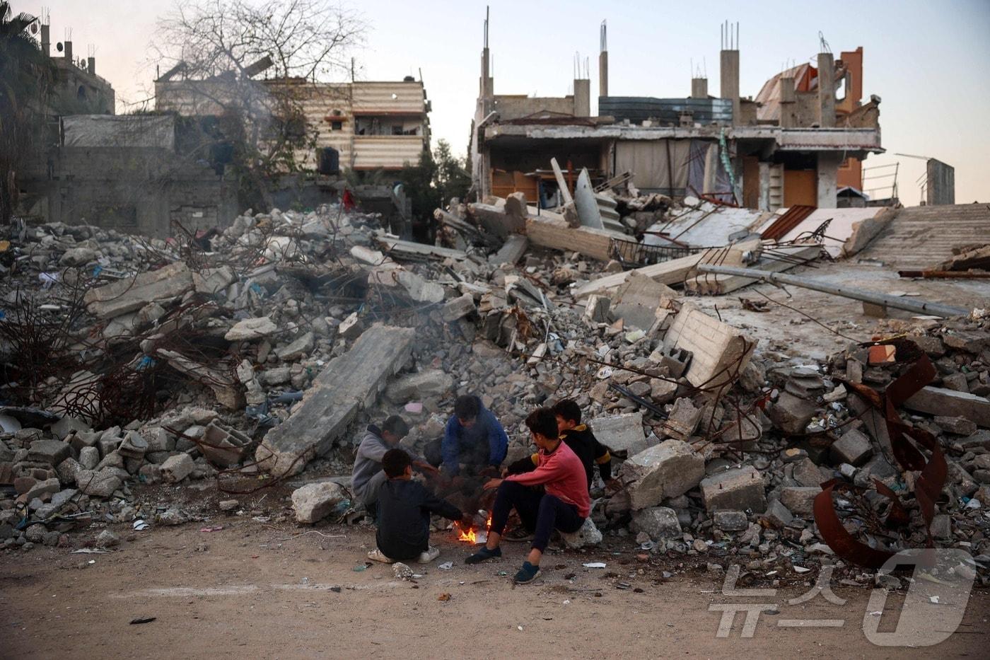 2일(현지시간) 팔레스타인 가자지구 부레이 난민 캠프에서 하마스와 전쟁 중인 이스라엘 군의 포격을 받아 무너진 건물 더미 옆에서 어린이들이 불을 쬐고 있다. 2025.01.03 ⓒ AFP=뉴스1 ⓒ News1 우동명 기자
