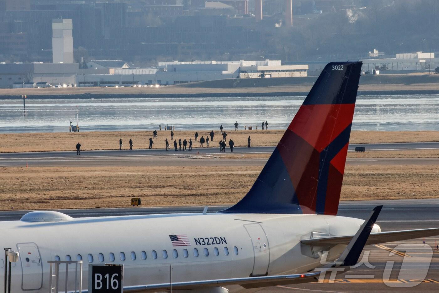 30일 미국 수도 워싱턴DC 인근 버지니아주 알링턴의 포토맥 강에 추락한 아메리칸이글 5342편과 블랙호크 헬기의 충돌 사고에 따른 구조작업을 위해 로널드레이건워싱턴국립공항 활주로를 응급 요원들이 걸어가고 있다. ⓒ 로이터=뉴스1 ⓒ News1 류정민 특파원
