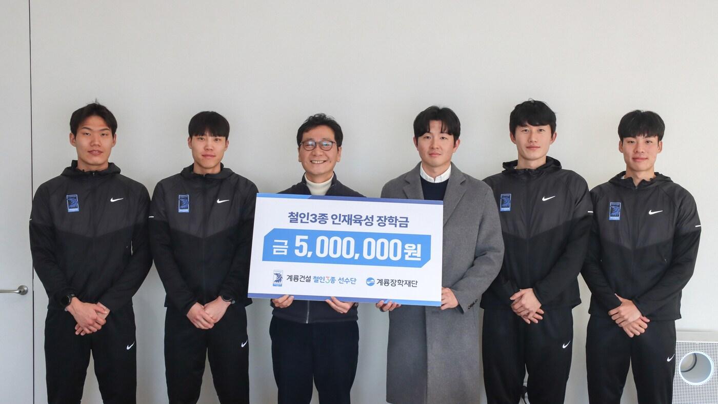 계룡건설 철인3종 선수단이 계룡장학재단 이승찬 이사장에게 철인3종 인재육성 장학금을 전달하고 기념촬영을 진행했다. 왼쪽부터 선수 권민호, 선수 최규서, 계룡장학재단 이사장 이승찬, 감독 신성근, 선수 박상민, 선수 박찬욱.(계룡건설 제공)