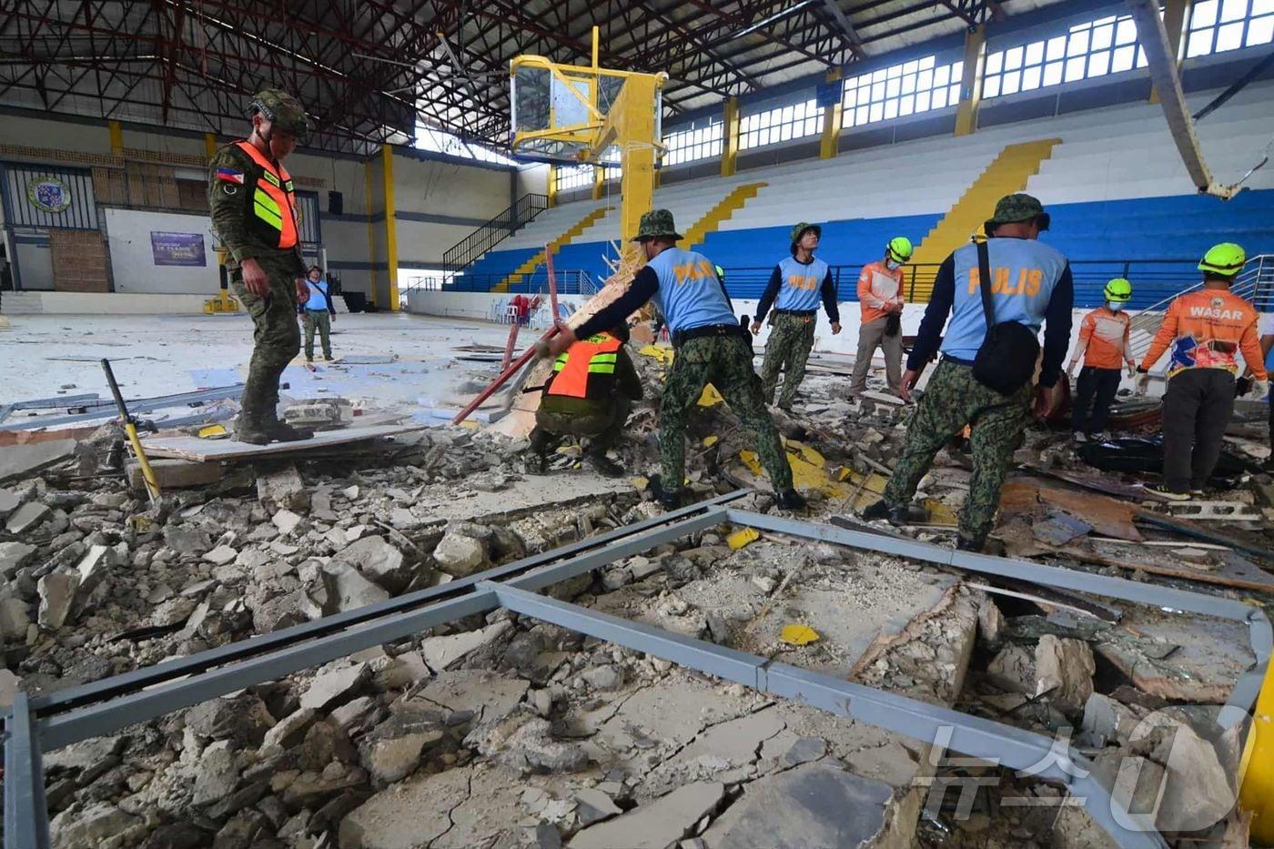 필리핀 경찰과 구조대원들이 1일(현지) 세부 레미히오 마을의 한 실내 경기장에서 발생한 피해를 점검하고 있다. 2025.10.01. ⓒ AFP=뉴스1 ⓒ News1 윤다정 기자