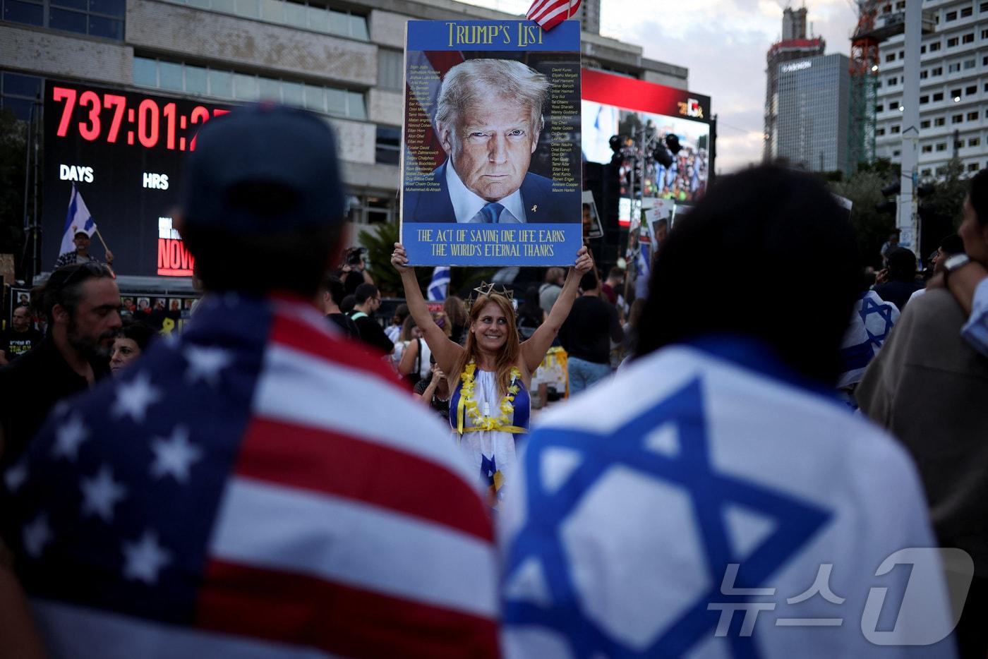 이스라엘의 인질 석방 환영 집회에서 한 참가자가 도널드 트럼프 미국 대통령의 사진을 들어보이고 있다. 2025.10.13 ⓒ 로이터=뉴스1 ⓒ News1 이지예 객원기자