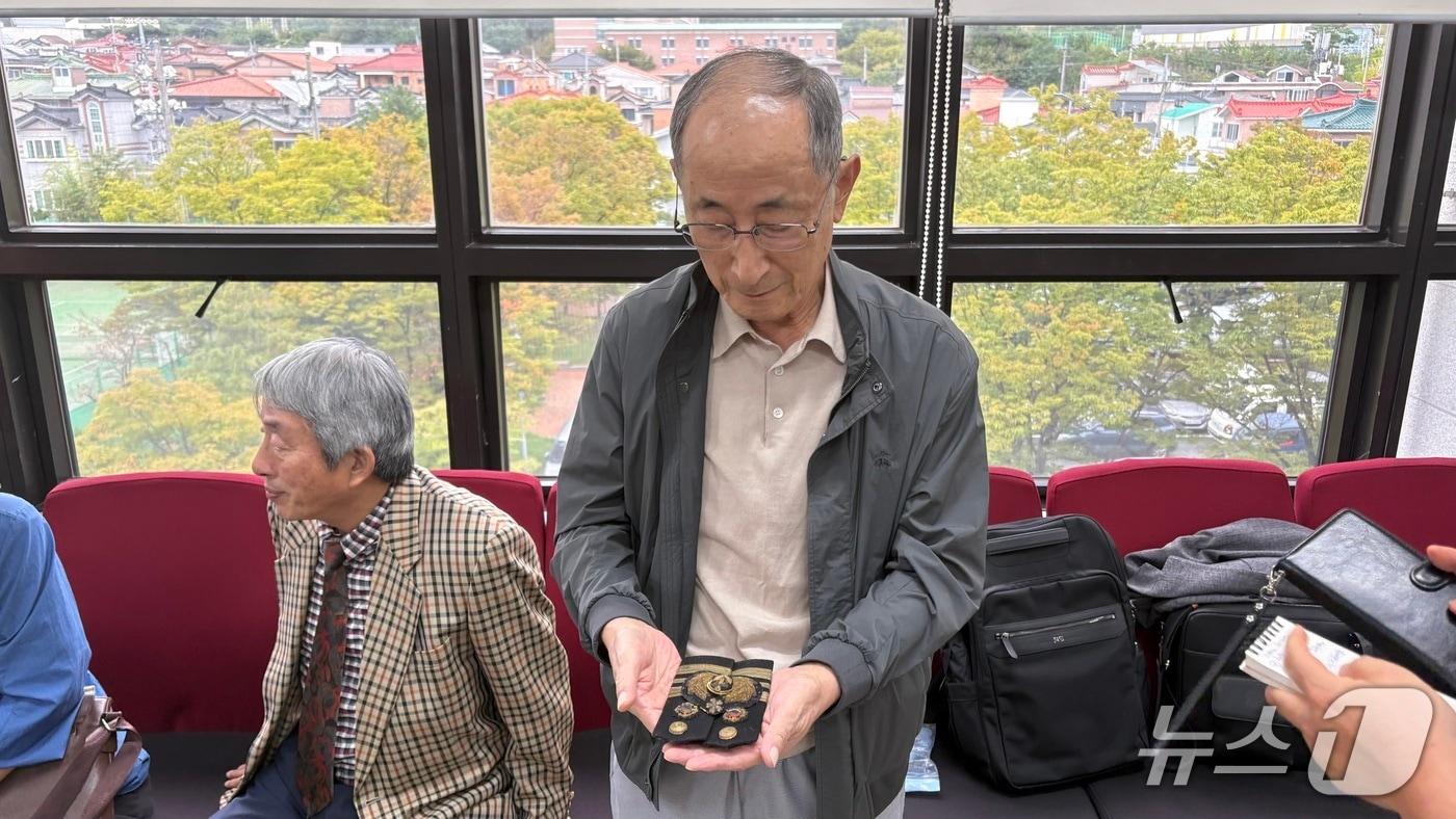 고&#40;故&#41; 이상규 소령의 장남 이동주 씨가 14일 창원지법 법정동에서 이 소령의 재심 첫 공판 직후 만난 취재진에게 이 소령의 계급장과 견장을 들어 보이고 있다.2025.10.14/뉴스1 강정태 기자