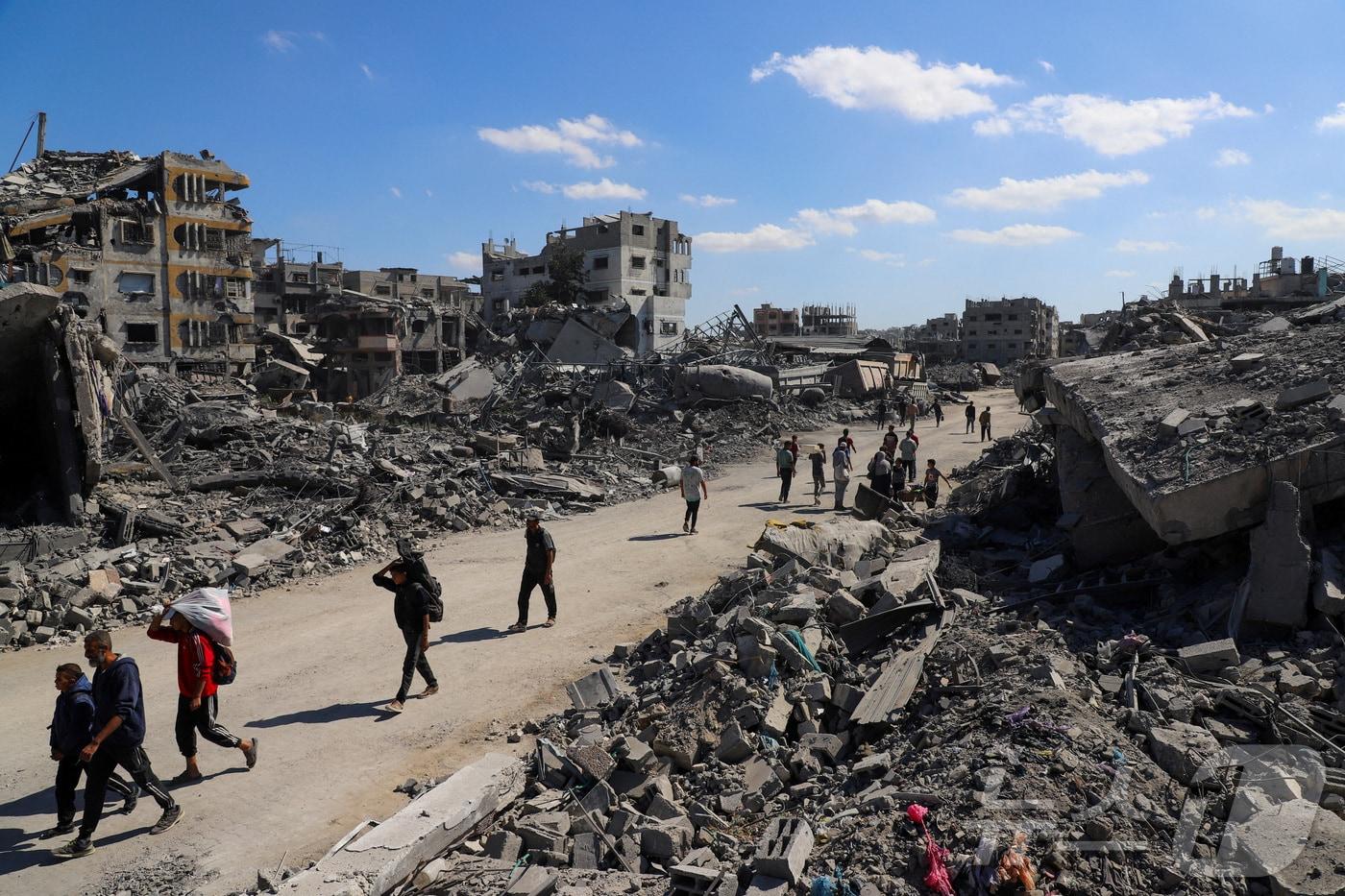 이스라엘과 하마스가 휴전에 돌입한 가운데 지난 14일&#40;현지시간&#41; 전쟁으로 파괴된 가자시티의 거리를 팔레스타인 주민들이 지나고 있다. 2025.10.14. ⓒ 로이터=뉴스1 