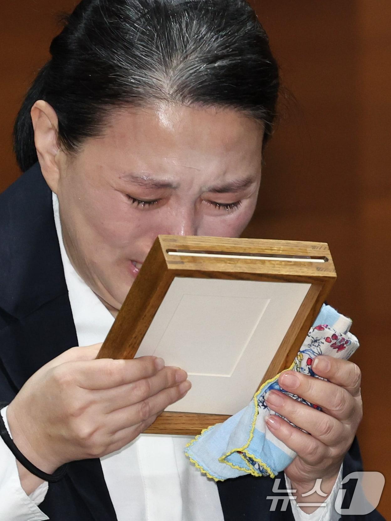 본문 이미지 - 15일 오전 서울시 마포구 상암동 MBC 상암사옥 골든마우스홀에서 열린 안형준 MBC 사장의 기자회견에서 직장 내 괴롭힘을 호소하며 스스로 목숨을 끊은 MBC 기상캐스터 오요안나 씨의 어머니 장연미씨가 명예사원증을 받고 눈물을 흘리고 있다. 2025.10.15/뉴스1 ⓒ News1 박정호 기자