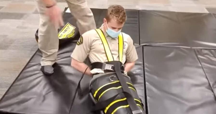 본문 이미지 - 미국 이민단속국(ICE) 요원이 WRAP이라고 불리는 전신 구속 장치 사용의 시범을 보이는 모습. (사진=CBS 시카고 보도 갈무리)