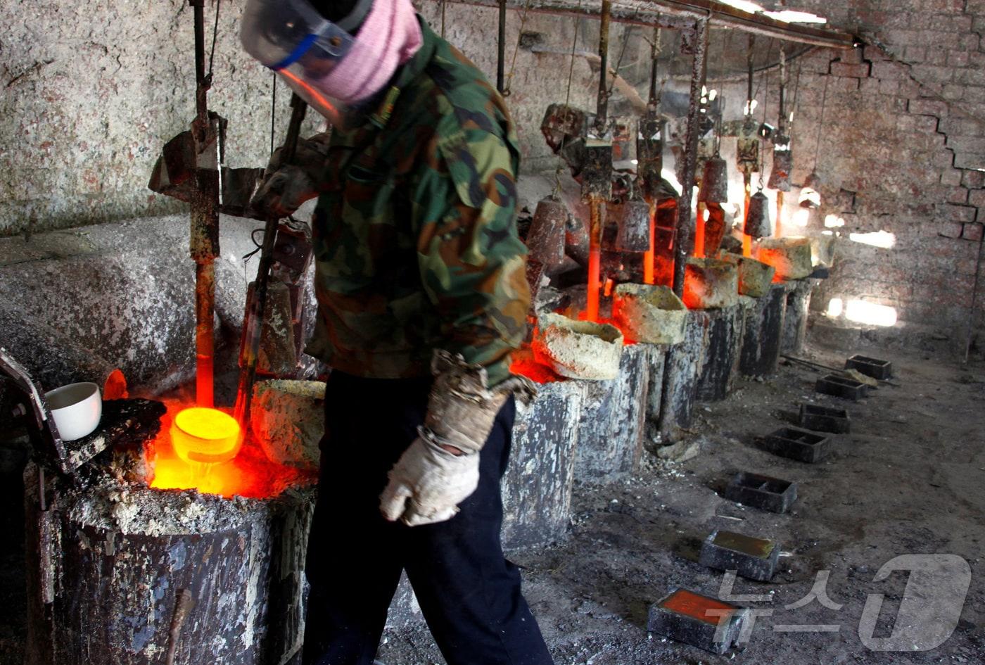 중국 내몽골 자치구 다마오 인근의 제련 작업장에서 한 노동자가 희토류 금속인 란타넘을 주형에 붓기 위해 준비하고 있다. 2010.10.31 ⓒ 로이터=뉴스1