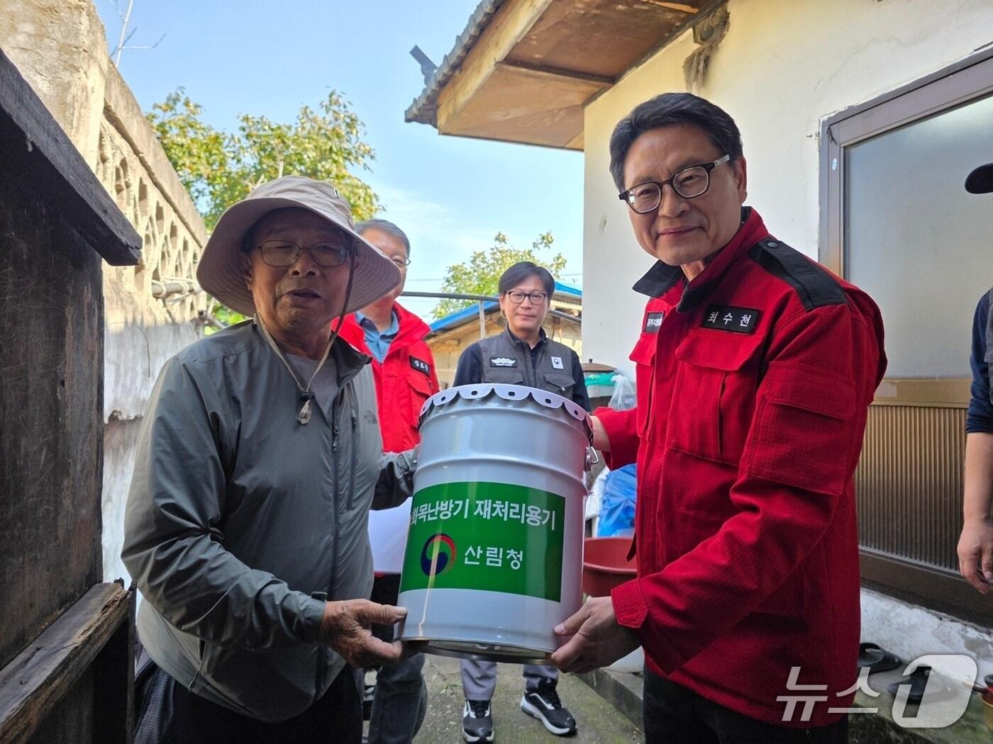 본문 이미지 - 최수천 동부지방산림청장(사진 오른쪽)이 화목 사용 농가에 재처리용기를 지급하고 있다.(동부산림청 제공, 재판매 및 DB 금지) 2025.10.2/뉴스1