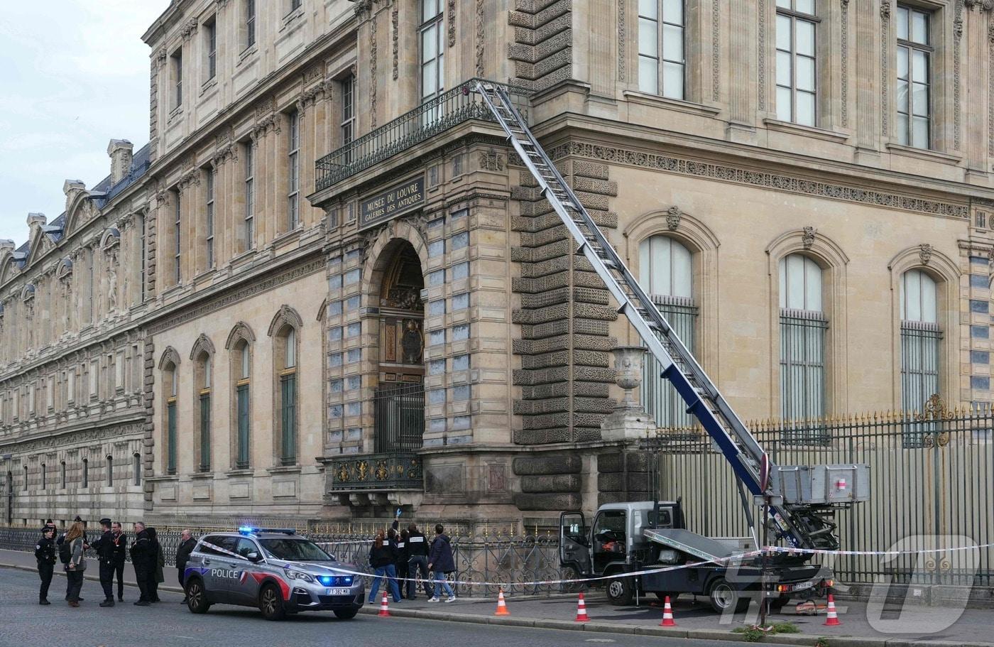 본문 이미지 - 19일(현지시간) 프랑스 파리 루브르 박물관에 침입한 강도들이 사용한 가구용 전동 사다리 옆에 현지 경찰관들이 서 있다. 2025.10.19 ⓒ AFP=뉴스1