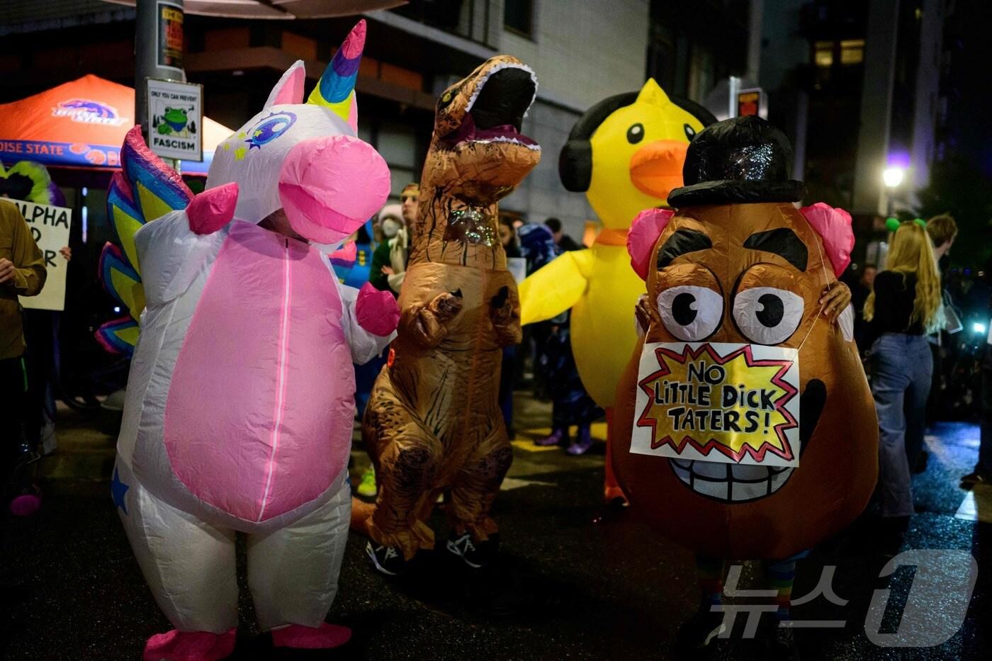 18일&#40;현지시간&#41; 미국 오리건주 포틀랜드에서 반이민세관단속국&#40;I.C.E.&#41; 시위대가 형형색색의 커다란 캐릭터 복장을 입고 이민세관단속국 건물 앞에서 춤을 추며 퍼포먼스를 펼치고 있다. 그중 감자 인형의 가슴에는 &#34;No Little Dick Taters!&#34;라는 문구가 적혀 있는데, 이는 &#39;작은 독재자 따위는 사절!&#39;이라는 의미의 말장난으로, 영어 단어 dictators&#40;독재자&#41;를 dick taters로 익살스럽게 비튼 표현이다. dick은 권위적인 사람 혹은 남성 성기를 지칭하는 표현이고 taters는 감자라는 뜻이다.  ⓒ AFP=뉴스1