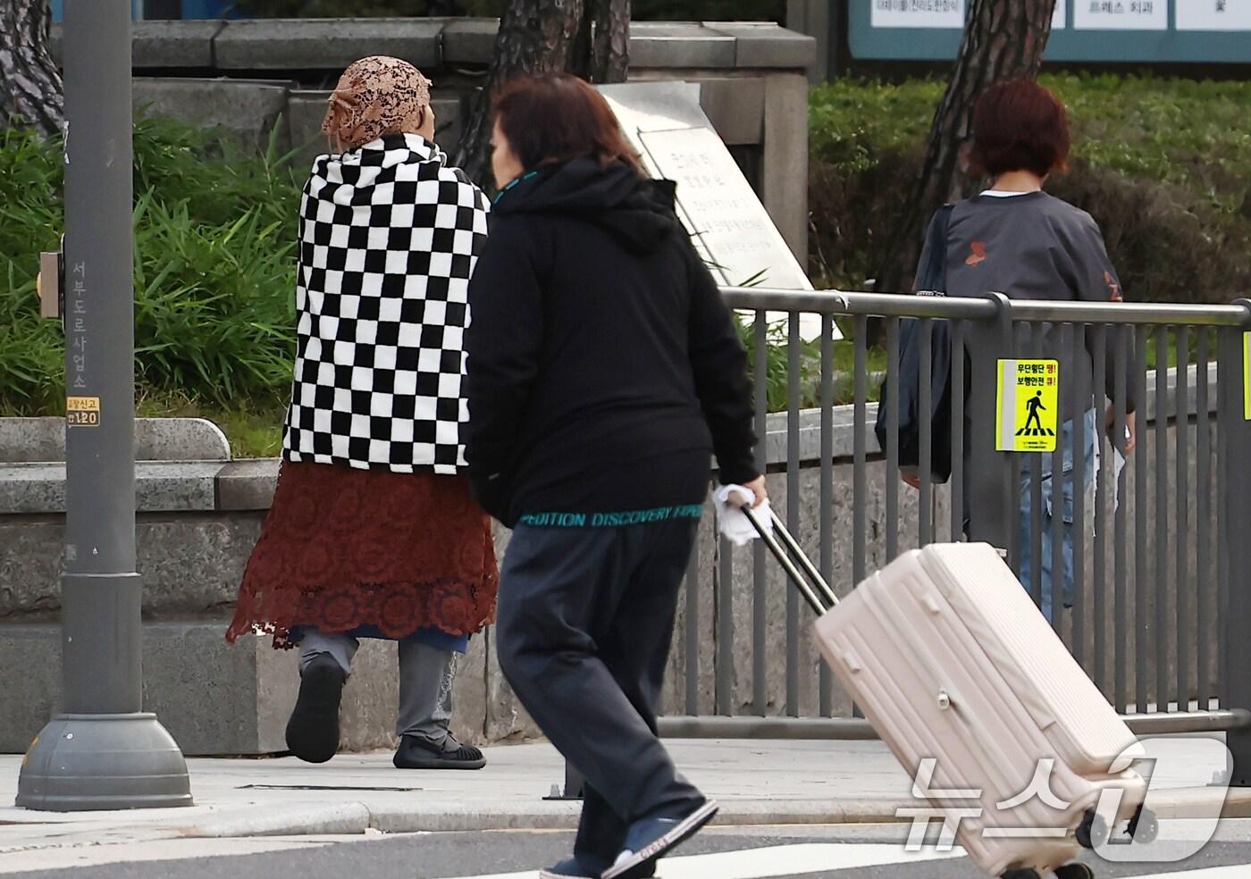 서울을 비롯한 대부분 지역의 아침 최저 기온이 한 자릿수로 떨어지며 올가을 가장 추운 날씨를 보인 20일 오전 서울 시청역 인근에서 담요를 두른 시민이 이동하고 있다. 2025.10.20/뉴스1 ⓒ News1 김민지 기자