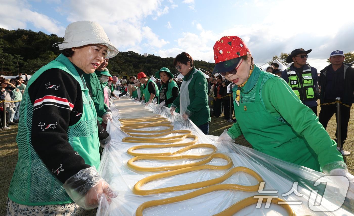 ‘제24회 이천쌀문화축제’가 개막한 22일 경기 이천시 모가면 이천농업테마공원에서 행사 관계자들이 600m 가래떡을 만들고 있다. ⓒ News1 김영운 기자