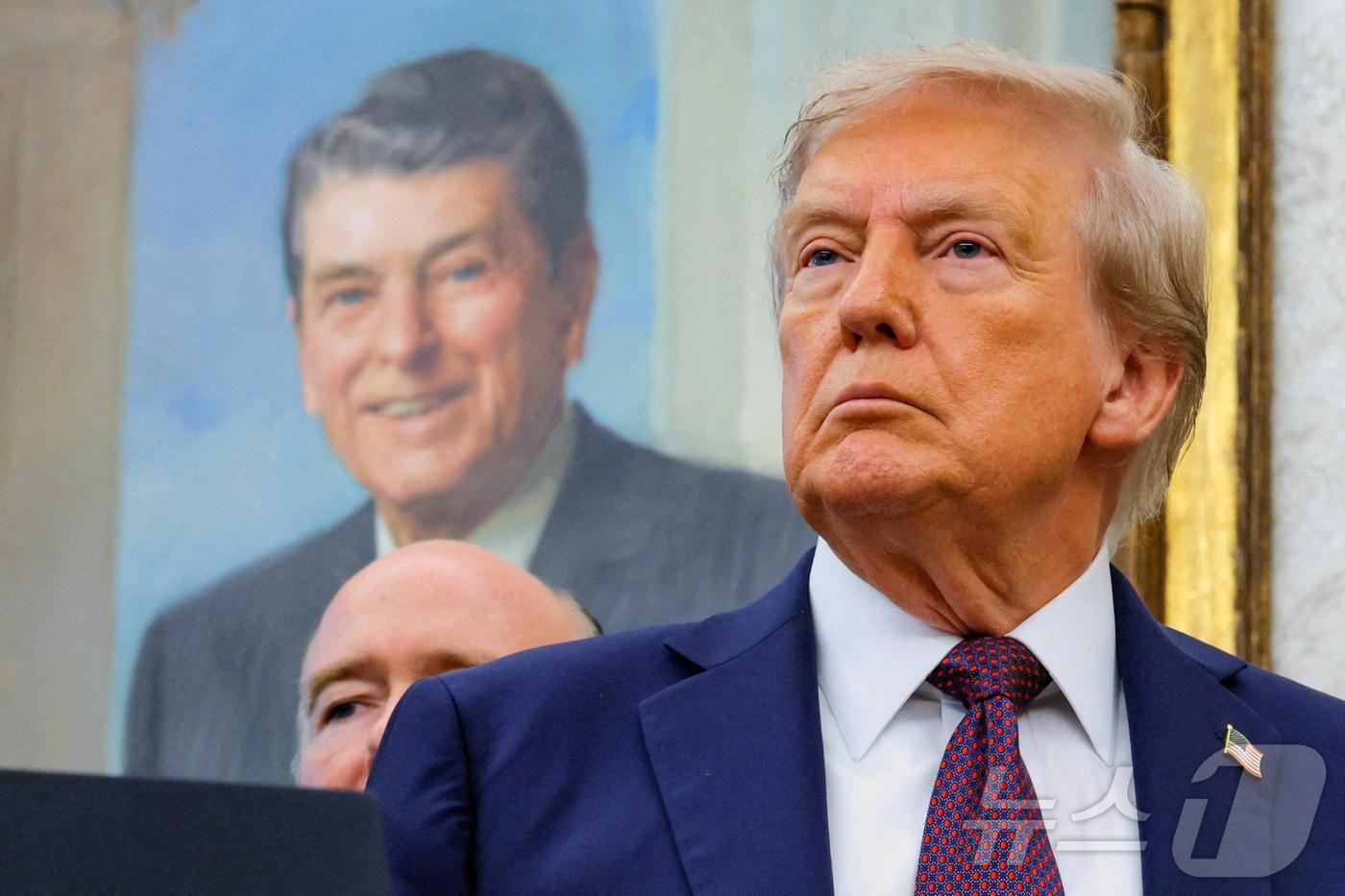 백악관 오벌오피스&#40;미 대통령 집무실&#41;에 걸려 있는 로널드 레이건 전 대통령 앞에 서 있는 도널드 트럼프 미국 대통령. ⓒ 로이터=뉴스1 ⓒ News1 류정민 특파원