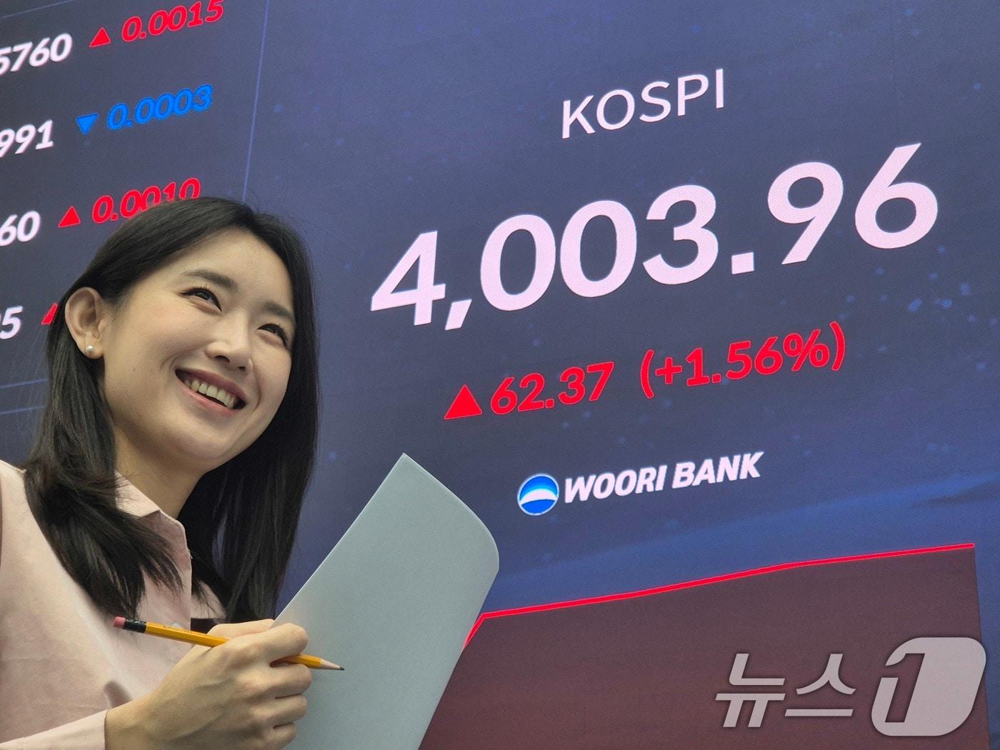 본문 이미지 - 코스피지수가 사상 처음 4000선을 돌파한 27일 오전 서울 중구 우리은행 본점 딜링룸에서 직원이 환하게 웃고 있다. 코스피 지수는 지난 6월 20일 3021.84으로 마감하면서 3000선을 넘은 뒤 약 4개월 만에 4000선을 넘어섰다. &#40;우리은행 제공. 재판매 및 DB 금지&#41; 2025.10.27/뉴스1 ⓒ News1 박지혜 기자