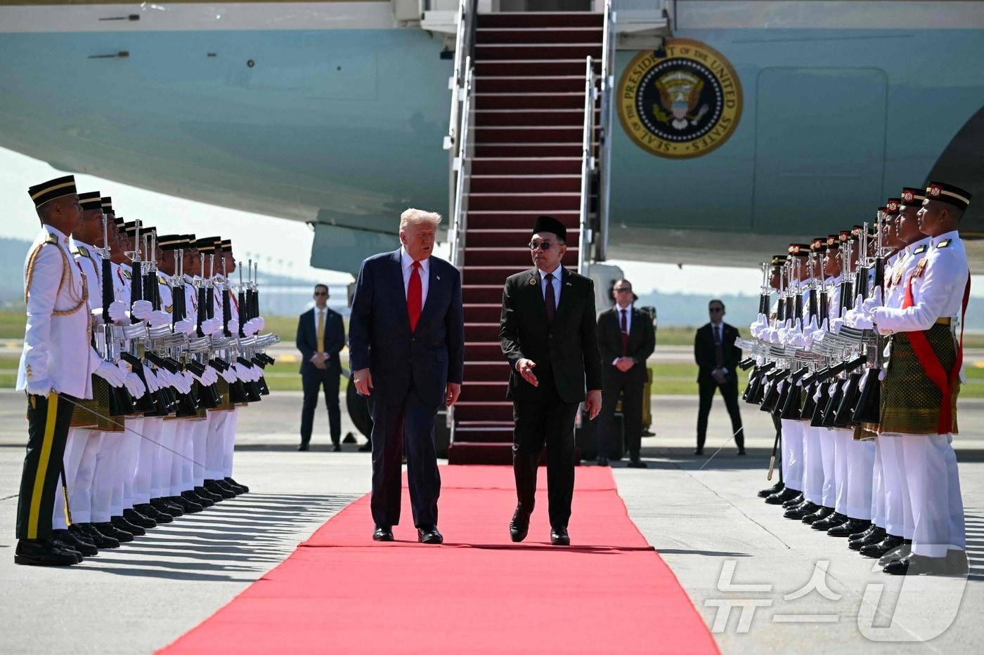 26일 도널드 트럼프 미국 대통령이 말레이시아 쿠알라룸푸르 국제공항에 도착해 전용기에서 내린 뒤 안와르 이브라힘 말레이시아 총리와 함께 걷고 있다. 트럼프 대통령은 이날 말레이시아를 시작으로 아시아 순방에 나섰으며, 이번 일정에는 시진핑 중국 국가주석과의 중대한 통상 협상이 포함돼 있다.2025.10.26.ⓒ AFP=뉴스1