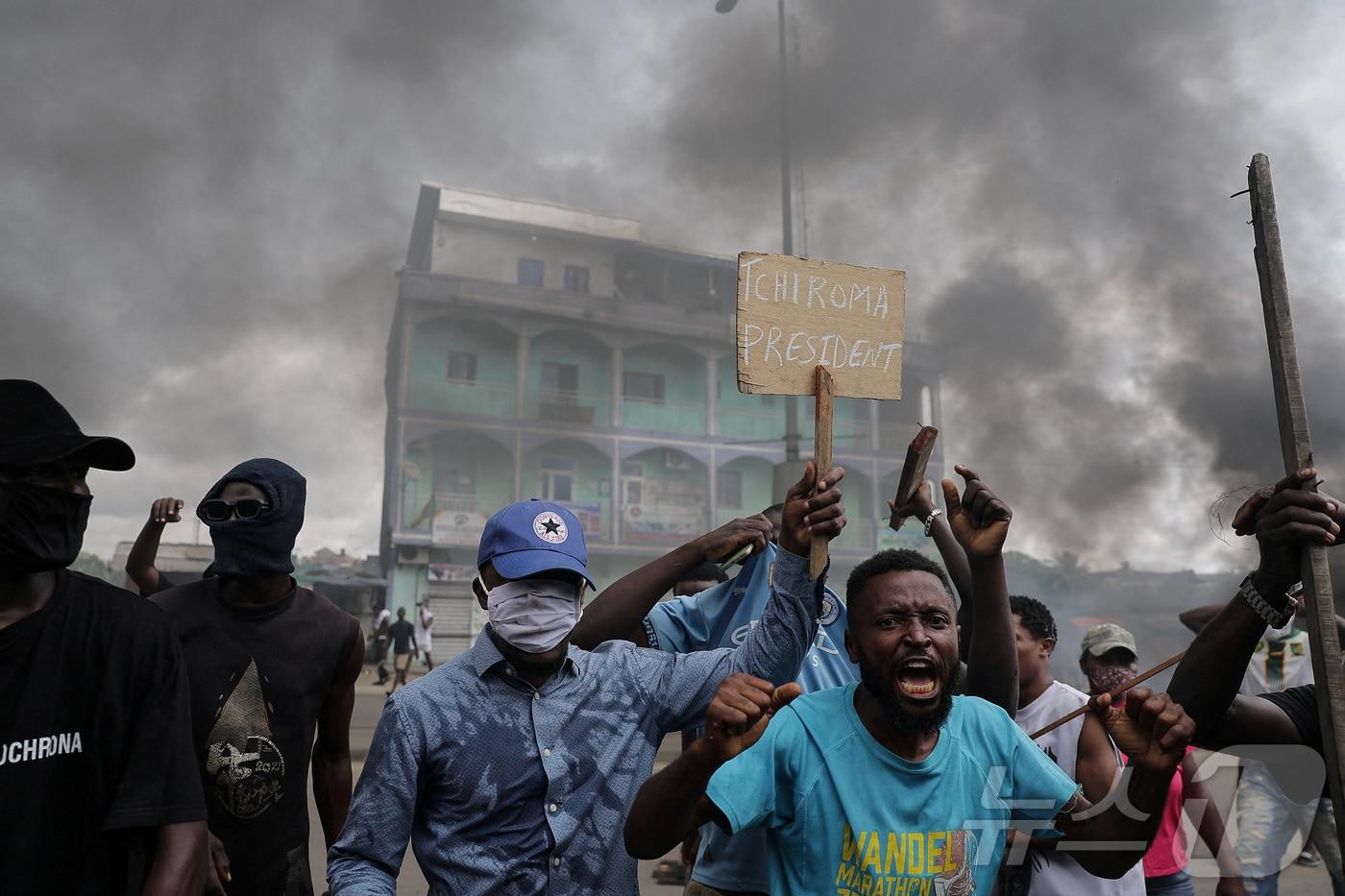 카메룬 헌법위원회가 10월 27일(현지시간) 폴 비야 대통령의 승리를 선언한 뒤, 카메룬 두알라에서 야권 후보인 이사 치로마 바카리의 지지자들이 보안군과 충돌하는 가운데 한 남성이 '치로마 대통령'이라고 쓰인 피켓을 들고 있다. 2025.10.27. ⓒ 로이터=뉴스1 ⓒ News1 윤다정 기자