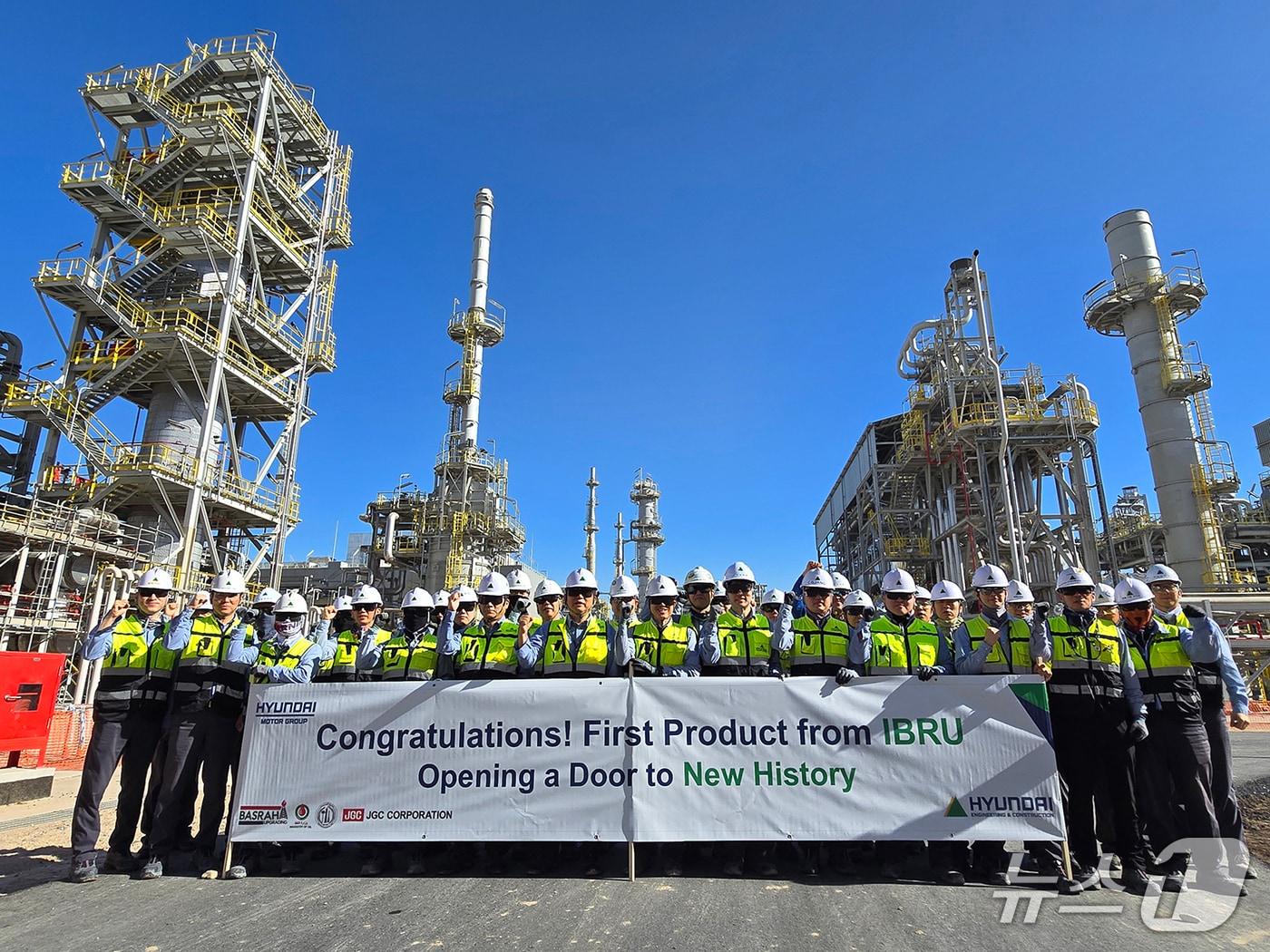 본문 이미지 - 가솔린 생산을 축하하는 플래카드를 들고 이라크 바스라 정유공장 고도화설비 공사 현장 임직원들이 기념사진을 촬영하고 있다. (현대건설 제공) 뉴스1 ⓒ News1