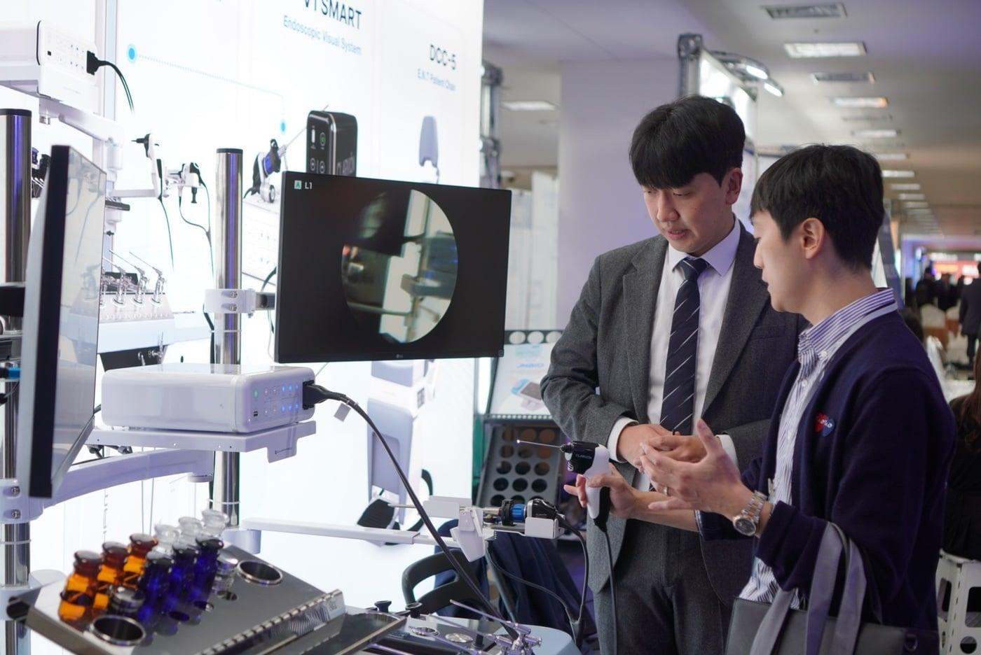 본문 이미지 -  제31차 이비인후과 종합학술대회에서 동아참메드 임직원이 관람객에게 진료용 내시경 'V1 SMART'를 소개하고 있다. (동아제약 제공)